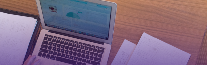 A laptop with papers near it.